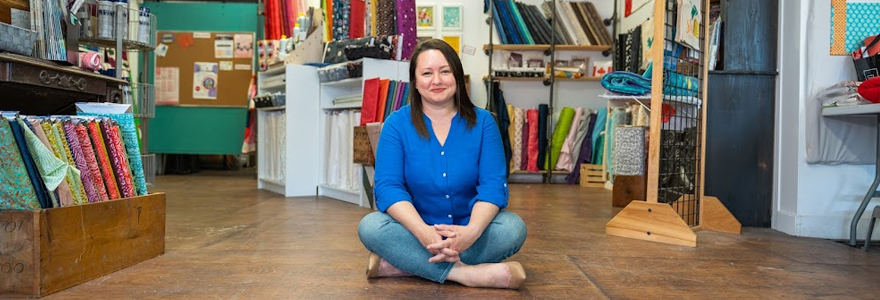 Rachel Halaney sitting on the floor surrounded by colourful fabrics